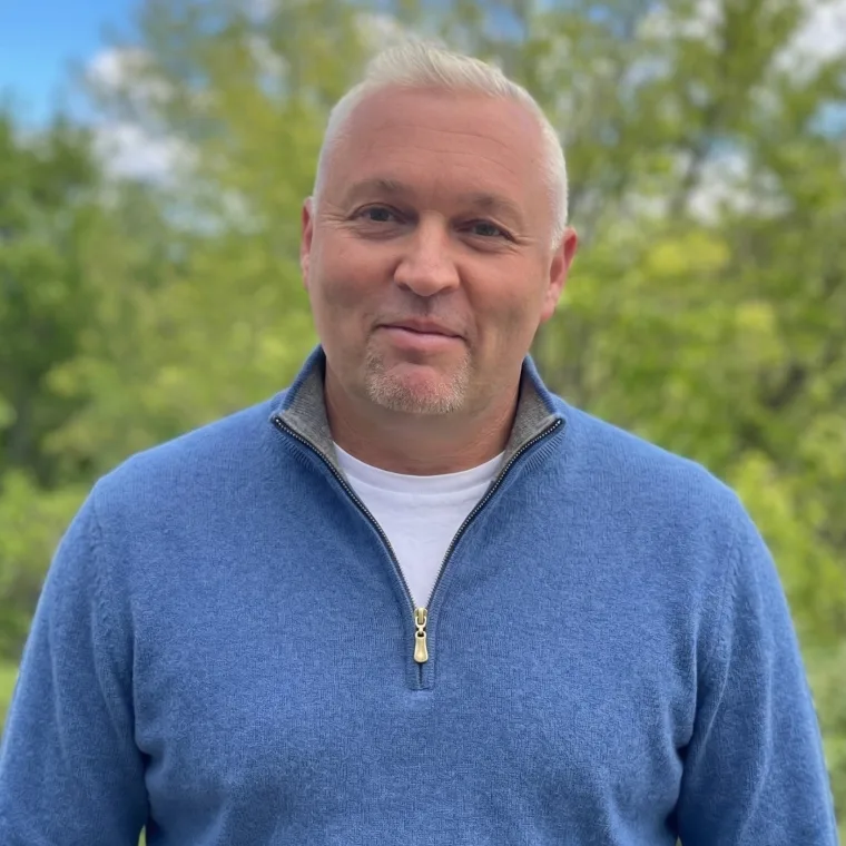 Stephan Waltl, Gründer von microgast, im blauen Pullover vor grünen Bäumen